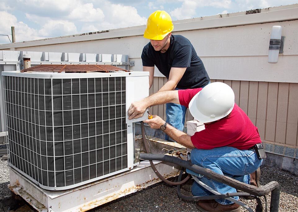 two people working on hvac unit on a rooftop