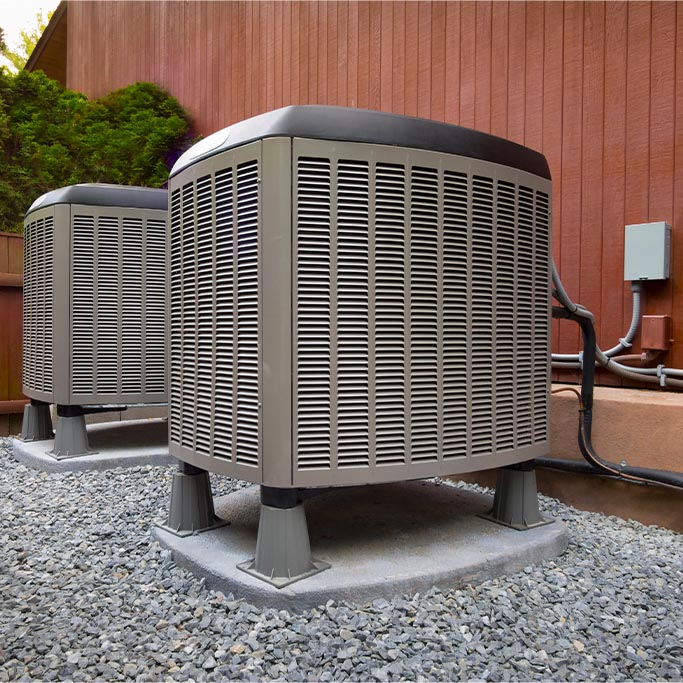 two air conditioning units in front of a brown wooden wall